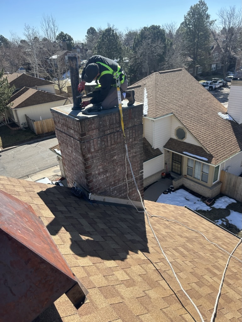 Chimney cleaning technician working on rooftop